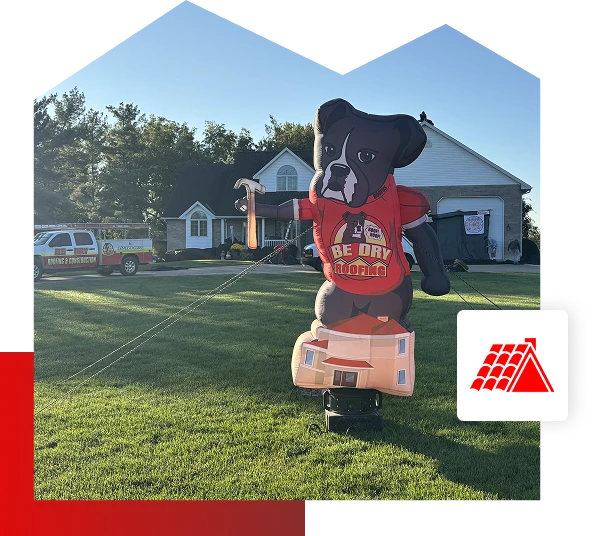 A large inflatable dog wearing a red BE DRY ROOFA! shirt stands on a green lawn in front of a suburban house in Quincy IL, promoting Be Dry Roofing services, with a van parked nearby on a sunny day.