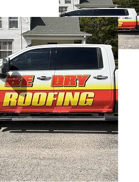 A truck with a red, yellow, and orange design is parked in front of a house in Quincy IL. Large text on the side reads BE DRY ROOFING, highlighting their expert roofing services.